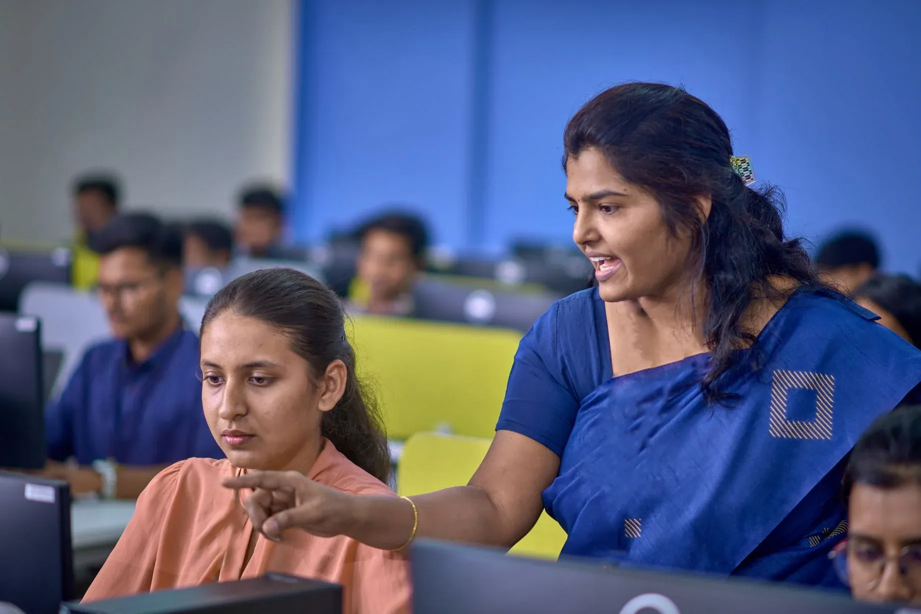 A lecturer sharing insights with a student in front of a computer.